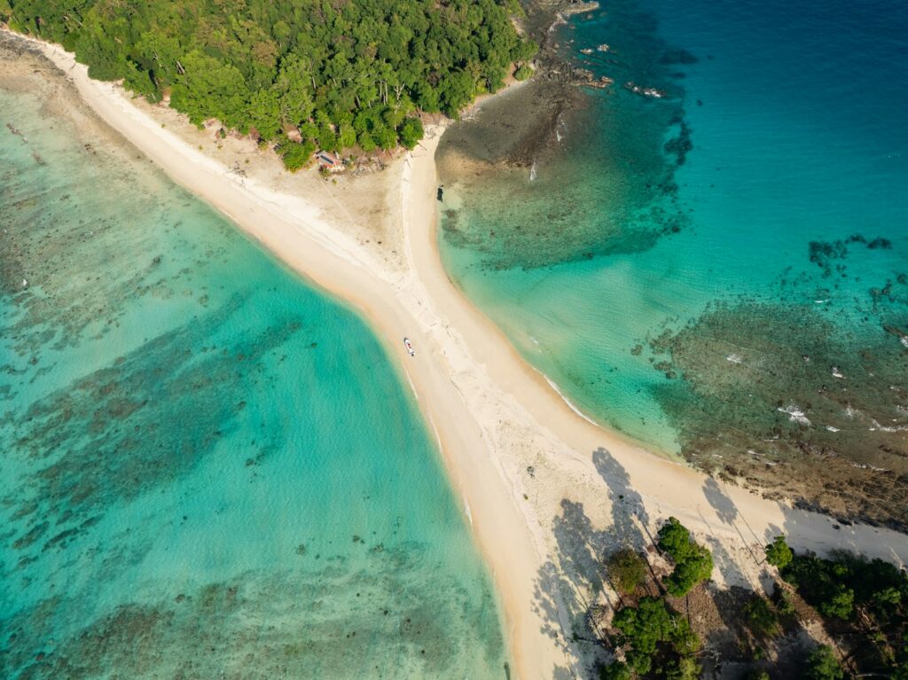 Aerial view of a sandbar dividing turquoise tropical ocean.